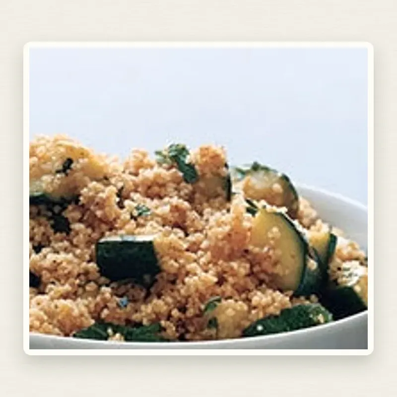 Couscous with Spiced Zucchini plated on an off-white linen surface