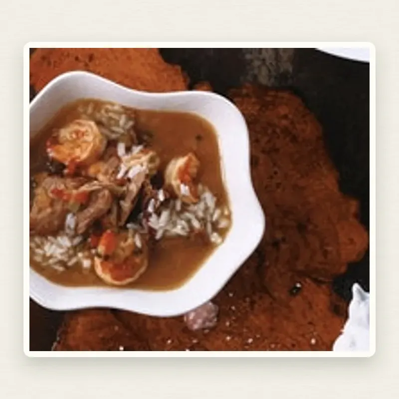 Duck and Shrimp Gumbo plated on an off-white linen surface